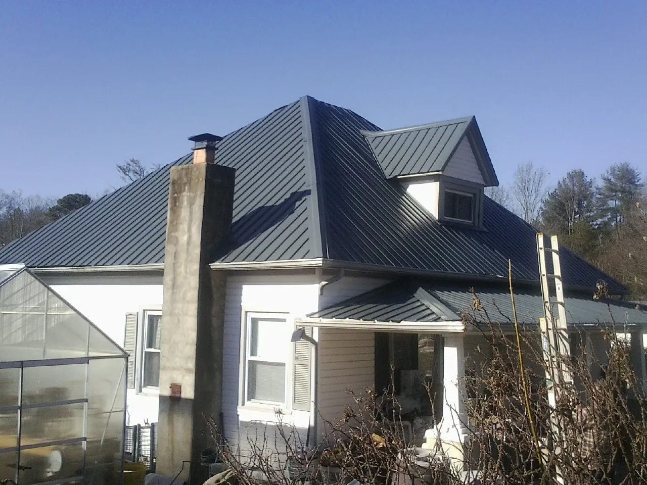 Dark blue standing seam metal roof on a white farmhouse with dormer — Slate & Tile Roof Repair by Roofing Brothers in Taylorsville
