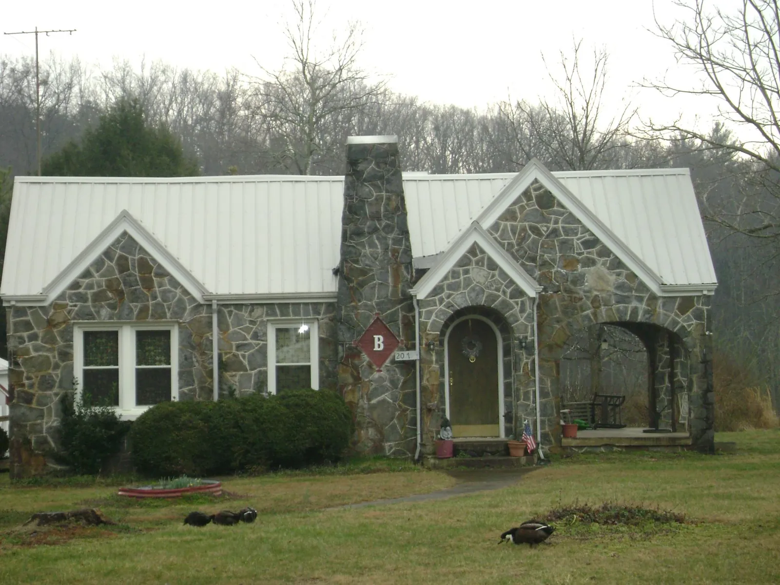 White metal roof on a stone cottage with steep gables in Taylorsville
