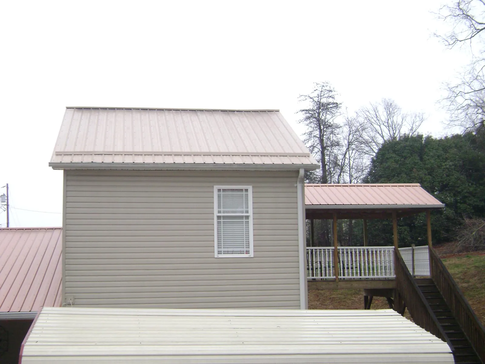 Tan metal roofs on a two story addition and attached porch, from a Roof Replacement job in Taylorsville